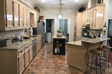 Elegant galley brown floor eat-in kitchen photo in Jackson with an undermount sink, beaded inset cabinets, light wood cabinets, granite countertops, multicolored backsplash, glass tile backsplash, stainless steel appliances and an island