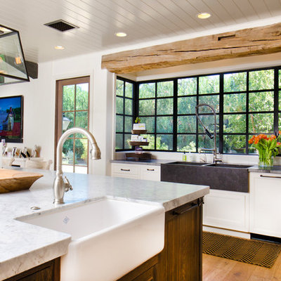 Example of a farmhouse l-shaped medium tone wood floor open concept kitchen design in Phoenix with a farmhouse sink, shaker cabinets, white cabinets and an island