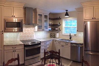Rustik inredning av ett kök, med en dubbel diskho, luckor med upphöjd panel, beige skåp, granitbänkskiva, vitt stänkskydd, stänkskydd i terrakottakakel, rostfria vitvaror och brunt golv