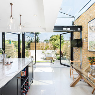 This is an example of a medium sized contemporary kitchen/diner in London with a belfast sink, granite worktops, an island and white floors.