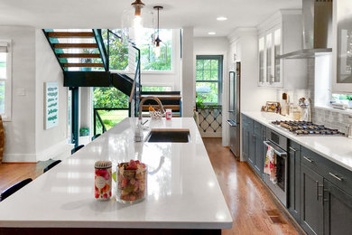 Example of a large transitional single-wall light wood floor and brown floor eat-in kitchen design in DC Metro with an undermount sink, shaker cabinets, gray cabinets, quartz countertops, gray backsplash, subway tile backsplash, stainless steel appliances, an island and white countertops