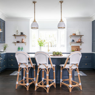 Traditional eat-in kitchen designs - Example of a classic u-shaped dark wood floor and brown floor eat-in kitchen design in Houston with a farmhouse sink, blue cabinets, white backsplash, stainless steel appliances, an island, white countertops and shaker cabinets