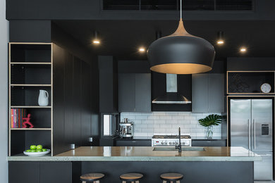 Small urban u-shaped open plan kitchen in Melbourne with an integrated sink, black cabinets, concrete worktops, white splashback, metro tiled splashback, stainless steel appliances, concrete flooring and a breakfast bar.