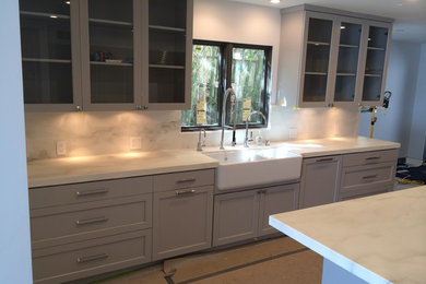 Kitchen pantry - large contemporary u-shaped kitchen pantry idea in Los Angeles with shaker cabinets, gray cabinets, solid surface countertops, white backsplash and an island