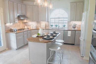 Mid-sized transitional u-shaped ceramic tile enclosed kitchen photo in Houston with an undermount sink, raised-panel cabinets, gray cabinets, granite countertops, beige backsplash, travertine backsplash, stainless steel appliances and an island
