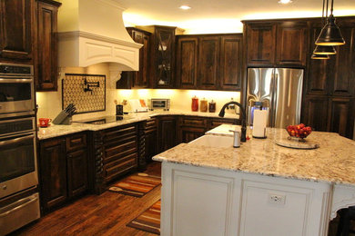 Open concept kitchen - mid-sized traditional l-shaped dark wood floor open concept kitchen idea in Dallas with a farmhouse sink, raised-panel cabinets, dark wood cabinets, granite countertops, beige backsplash, ceramic backsplash, stainless steel appliances and an island