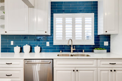 Modelo de cocina costera con puertas de armario blancas, salpicadero azul y encimeras blancas