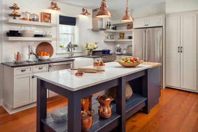 Inspiration for a mid-sized transitional l-shaped medium tone wood floor eat-in kitchen remodel in Wilmington with a farmhouse sink, shaker cabinets, white cabinets, white backsplash, subway tile backsplash, stainless steel appliances, an island and quartz countertops
