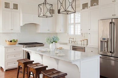 Kitchen - traditional l-shaped medium tone wood floor kitchen idea in Richmond with a farmhouse sink, shaker cabinets, white cabinets, marble countertops, white backsplash, subway tile backsplash, stainless steel appliances and an island