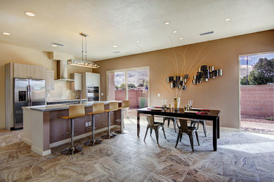 Open concept kitchen - large contemporary galley limestone floor open concept kitchen idea in Albuquerque with an undermount sink, flat-panel cabinets, gray cabinets, white backsplash, subway tile backsplash, stainless steel appliances, an island and solid surface countertops