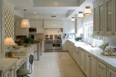 Inspiration for a large transitional l-shaped light wood floor open concept kitchen remodel in Bridgeport with a farmhouse sink, beaded inset cabinets, white cabinets, marble countertops, white backsplash, stone slab backsplash, stainless steel appliances and an island