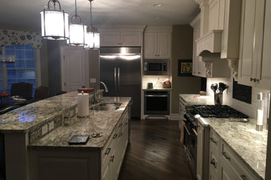 Example of a mid-sized classic l-shaped medium tone wood floor and brown floor eat-in kitchen design in Other with a double-bowl sink, raised-panel cabinets, white cabinets, granite countertops, stainless steel appliances and an island