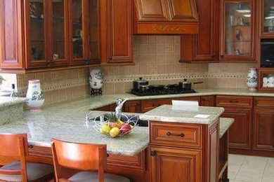 Inspiration for a mid-sized timeless u-shaped ceramic tile and beige floor enclosed kitchen remodel in New York with an undermount sink, raised-panel cabinets, medium tone wood cabinets, granite countertops, beige backsplash, ceramic backsplash, stainless steel appliances and a peninsula