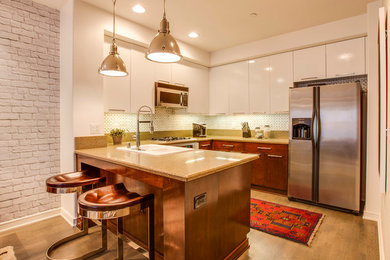 Example of a mid-sized trendy u-shaped medium tone wood floor eat-in kitchen design in Los Angeles with a drop-in sink, flat-panel cabinets, white cabinets, granite countertops, white backsplash, stainless steel appliances and a peninsula