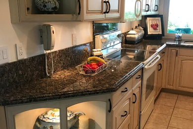 Inspiration for a mid-sized timeless u-shaped ceramic tile and beige floor kitchen remodel in San Diego with an undermount sink, raised-panel cabinets, beige cabinets, granite countertops, white appliances and no island
