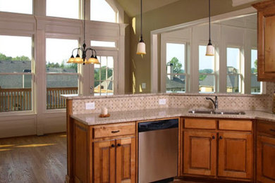 Eat-in kitchen - mid-sized transitional u-shaped medium tone wood floor and brown floor eat-in kitchen idea in Dallas with an undermount sink, raised-panel cabinets, medium tone wood cabinets, granite countertops, beige backsplash, ceramic backsplash and stainless steel appliances