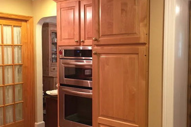 シカゴにある高級な中くらいなトラディショナルスタイルのおしゃれな独立型キッチン (レイズドパネル扉のキャビネット、淡色木目調キャビネット、シルバーの調理設備、淡色無垢フローリング) の写真