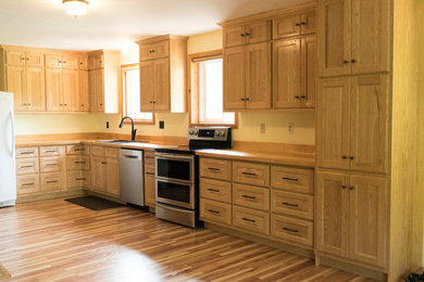 Eat-in kitchen - large transitional l-shaped linoleum floor and beige floor eat-in kitchen idea in Other with a double-bowl sink, flat-panel cabinets, light wood cabinets, wood countertops, stainless steel appliances, no island and brown countertops