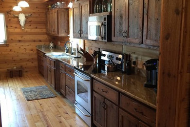 Example of a large mountain style single-wall light wood floor and beige floor eat-in kitchen design in Other with an undermount sink, recessed-panel cabinets, dark wood cabinets, granite countertops, brown backsplash, wood backsplash, stainless steel appliances and no island