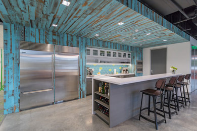 Mid-sized minimalist galley concrete floor and gray floor open concept kitchen photo in Portland with an undermount sink, flat-panel cabinets, white cabinets, quartzite countertops, blue backsplash, glass tile backsplash, stainless steel appliances and an island
