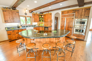 Kitchen - mid-sized cottage l-shaped medium tone wood floor and brown floor kitchen idea in San Diego with a farmhouse sink, flat-panel cabinets, medium tone wood cabinets, granite countertops, paneled appliances and an island