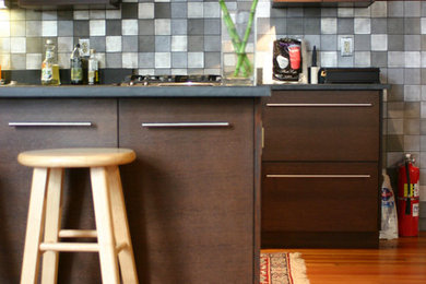 Foto de cocina comedor moderna con armarios con paneles lisos, puertas de armario de madera en tonos medios, encimera de cemento, salpicadero de metal, suelo de madera en tonos medios y una isla