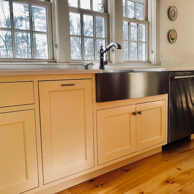 Inspiration for a mid-sized cottage l-shaped light wood floor and beige floor eat-in kitchen remodel in Other with a farmhouse sink, shaker cabinets, gray backsplash, metal backsplash, stainless steel appliances, an island, beige cabinets, solid surface countertops and white countertops