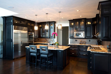 Transitional u-shaped enclosed kitchen photo in Calgary with an undermount sink, raised-panel cabinets, dark wood cabinets, granite countertops, metallic backsplash, porcelain backsplash and stainless steel appliances