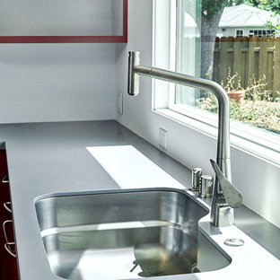 Offene, Mittelgroße Moderne Küche in U-Form mit Unterbauwaschbecken, flächenbündigen Schrankfronten, roten Schränken, Mineralwerkstoff-Arbeitsplatte, Küchenrückwand in Grau, Küchengeräten aus Edelstahl, braunem Holzboden, Kücheninsel, braunem Boden und grauer Arbeitsplatte in San Francisco