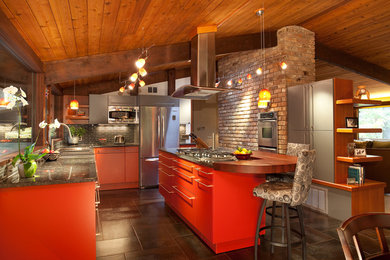 Bild på ett mellanstort funkis kök, med släta luckor, röda skåp, grått stänkskydd, rostfria vitvaror, en köksö, granitbänkskiva, en dubbel diskho, stänkskydd i stickkakel, klinkergolv i keramik och brunt golv