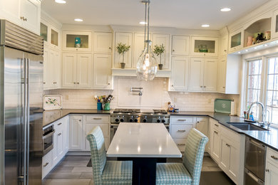 Large transitional u-shaped medium tone wood floor and brown floor eat-in kitchen photo in Other with an undermount sink, shaker cabinets, white cabinets, solid surface countertops, white backsplash, subway tile backsplash, stainless steel appliances and an island