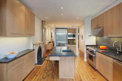 Example of a 1950s u-shaped kitchen design in New York with an undermount sink, flat-panel cabinets, light wood cabinets, granite countertops, gray backsplash, stone slab backsplash, stainless steel appliances and an island