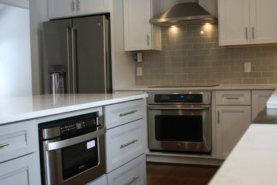 Example of a mid-sized minimalist u-shaped eat-in kitchen design in Baltimore with a farmhouse sink, recessed-panel cabinets, white cabinets, quartz countertops, beige backsplash, subway tile backsplash, stainless steel appliances and an island