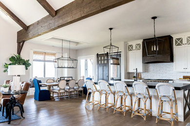 Large farmhouse single-wall medium tone wood floor open concept kitchen photo in Salt Lake City with a farmhouse sink, shaker cabinets, white cabinets, soapstone countertops, white backsplash, subway tile backsplash, stainless steel appliances, an island and black countertops