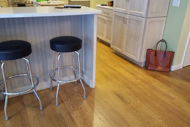 Example of a large country u-shaped medium tone wood floor kitchen design in Milwaukee with white cabinets and a peninsula