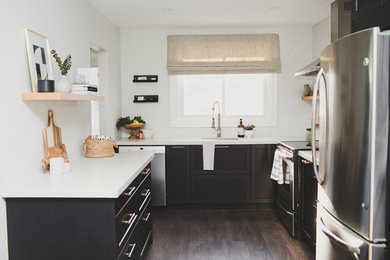 Open concept kitchen - small transitional l-shaped laminate floor and brown floor open concept kitchen idea in Toronto with shaker cabinets, black cabinets, solid surface countertops, gray backsplash, gray countertops, a single-bowl sink, porcelain backsplash and stainless steel appliances