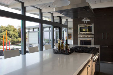 This is an example of a medium sized contemporary galley open plan kitchen in San Francisco with flat-panel cabinets, medium wood cabinets, grey splashback, stainless steel appliances and an island.
