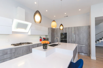Example of a large minimalist l-shaped light wood floor and gray floor eat-in kitchen design in San Francisco with an undermount sink, flat-panel cabinets, gray cabinets, quartz countertops, white backsplash, black appliances, an island and white countertops