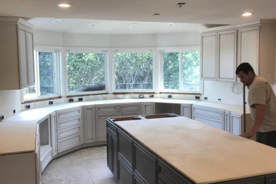 Large tuscan u-shaped eat-in kitchen photo in San Francisco with an undermount sink, flat-panel cabinets, white cabinets, quartzite countertops, white backsplash, porcelain backsplash, stainless steel appliances, an island and gray countertops