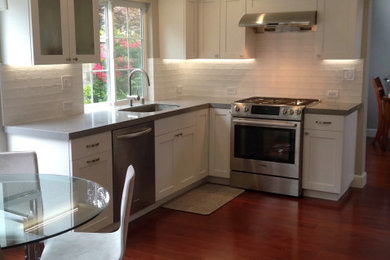Mid-sized transitional l-shaped medium tone wood floor and brown floor eat-in kitchen photo in San Francisco with an undermount sink, shaker cabinets, white cabinets, quartz countertops, white backsplash, subway tile backsplash, stainless steel appliances, no island and gray countertops