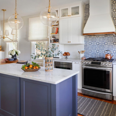 Eat-in kitchen - large country medium tone wood floor and brown floor eat-in kitchen idea in Philadelphia with a farmhouse sink, shaker cabinets, white cabinets, quartzite countertops, white backsplash, terra-cotta backsplash, stainless steel appliances, an island and white countertops