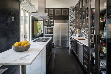 Example of an urban l-shaped dark wood floor and black floor kitchen design in Seattle with an undermount sink, marble countertops, stainless steel appliances, an island, glass-front cabinets, black cabinets, multicolored backsplash and matchstick tile backsplash