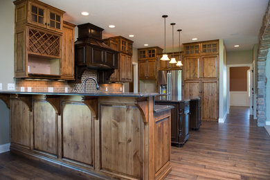Inspiration for a mid-sized rustic l-shaped medium tone wood floor eat-in kitchen remodel in Other with an undermount sink, raised-panel cabinets, medium tone wood cabinets, granite countertops, beige backsplash, stone tile backsplash and an island