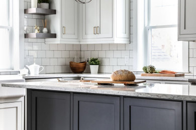 Eat-in kitchen - transitional l-shaped medium tone wood floor and brown floor eat-in kitchen idea in Boston with a farmhouse sink, beaded inset cabinets, white cabinets, quartz countertops, white backsplash, subway tile backsplash, stainless steel appliances, an island and gray countertops