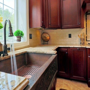 Mid-sized tuscan l-shaped travertine floor enclosed kitchen photo in Boston with a farmhouse sink, recessed-panel cabinets, dark wood cabinets, granite countertops, beige backsplash, stone tile backsplash, stainless steel appliances and an island