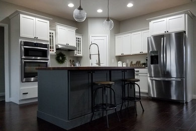 Inspiration for a large traditional l-shaped kitchen in Chicago with shaker cabinets, stainless steel appliances, medium hardwood flooring, an island and brown floors.