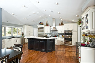 Example of a transitional dark wood floor eat-in kitchen design in Chicago with a drop-in sink, white cabinets, soapstone countertops, metallic backsplash, metal backsplash, stainless steel appliances and an island