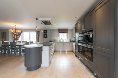 Medium sized modern u-shaped open plan kitchen in Other with shaker cabinets, grey cabinets and a breakfast bar.