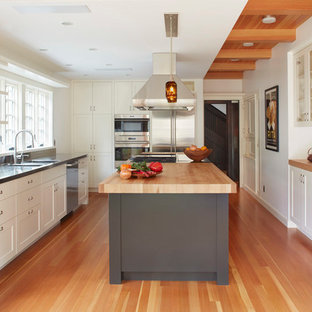 Design ideas for a transitional kitchen in San Francisco with an integrated sink, shaker cabinets, white cabinets, stainless steel benchtops, window splashback, stainless steel appliances, medium hardwood floors and with island.