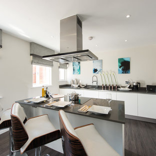 Medium sized contemporary l-shaped kitchen in Buckinghamshire with flat-panel cabinets, white cabinets, an island and black worktops.